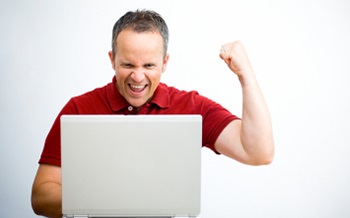 Man facing a computer giving a fist pump